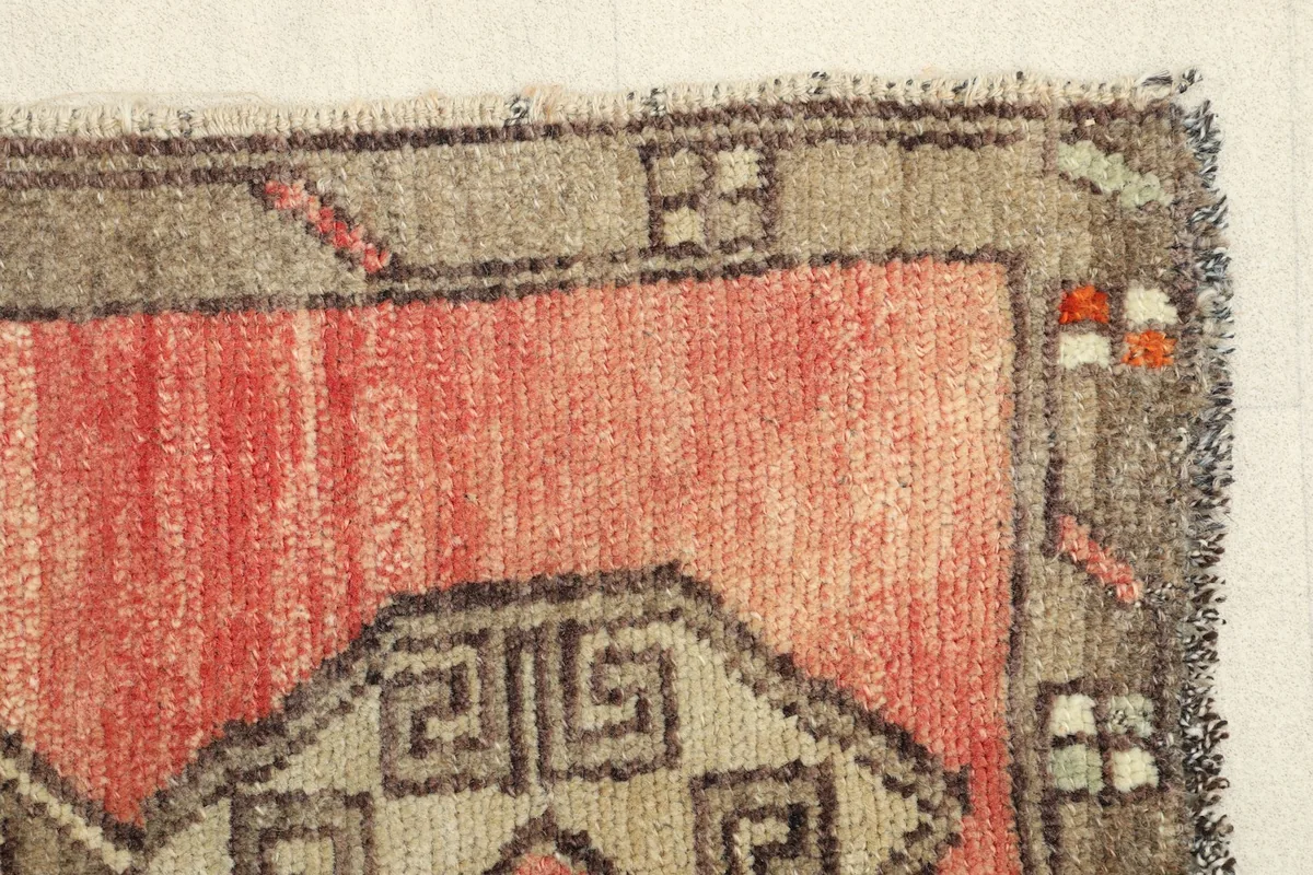 Detailed view of the rug's edge and border patterns, revealing slight wear consistent with age