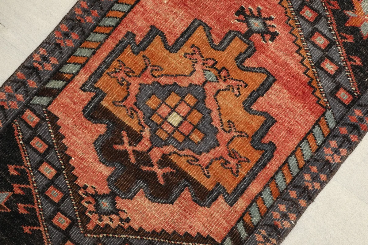 Close-up view of the central geometric medallion and surrounding tribal motifs in rust, orange, and gray tones.