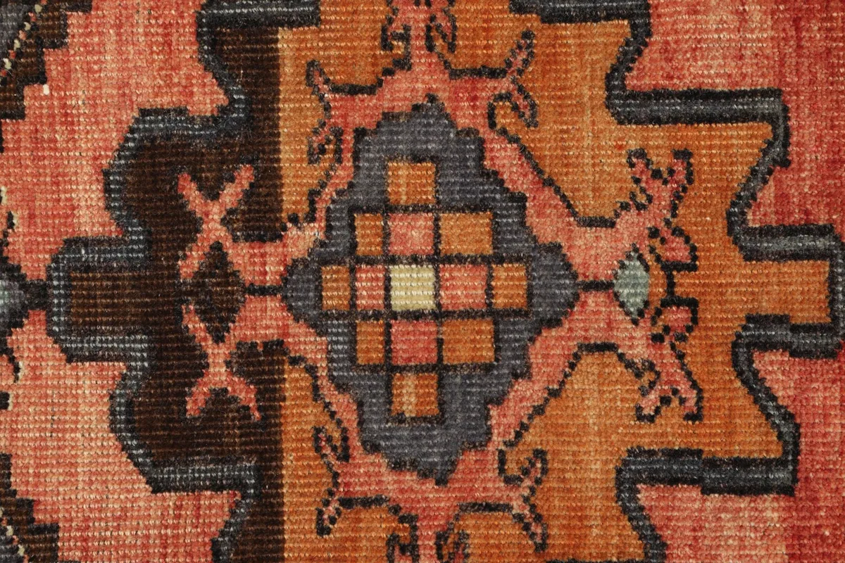 Detailed view of the hand-knotted wool pile, showing the intricate geometric design and color variations.