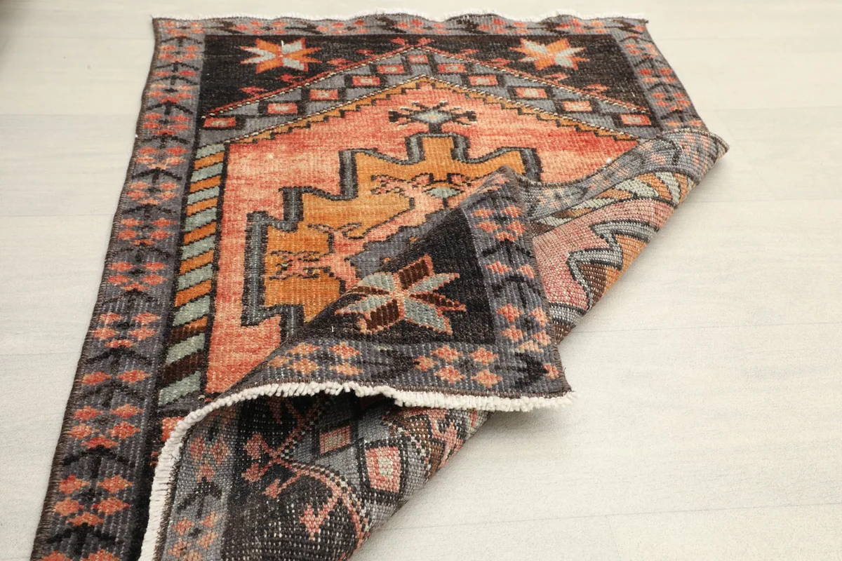 Partially folded rug, displaying the low pile and the texture of the vintage wool on both sides.