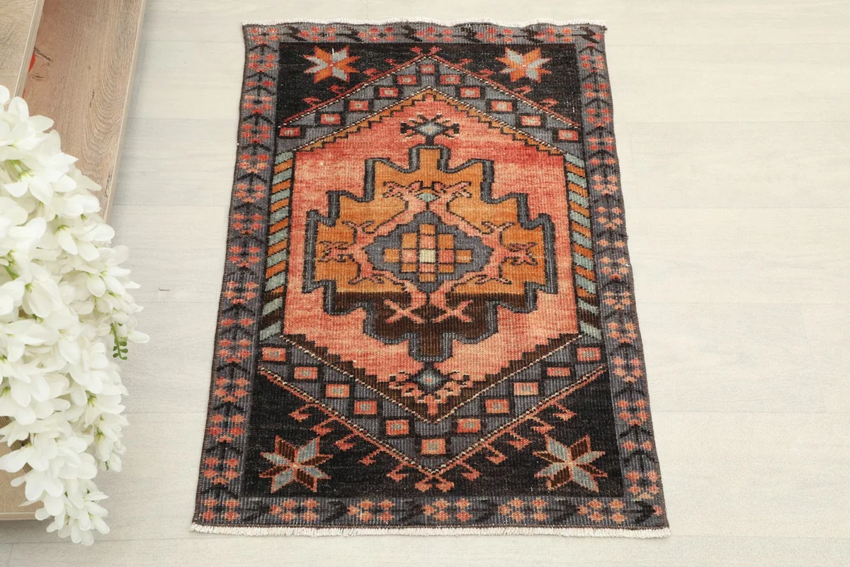 Overhead view of the vintage Anatolian rug, showcasing its rust field, charcoal border, and geometric patterns.