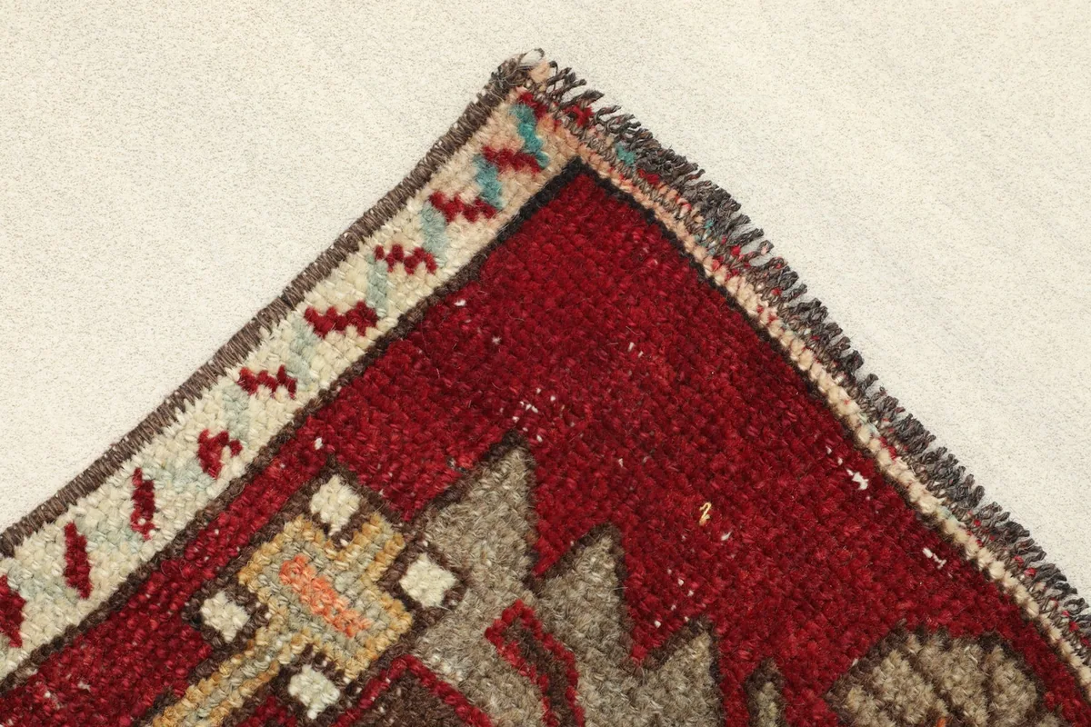 Corner detail showing the beige and brown border design and the short, natural fringe of the rug.