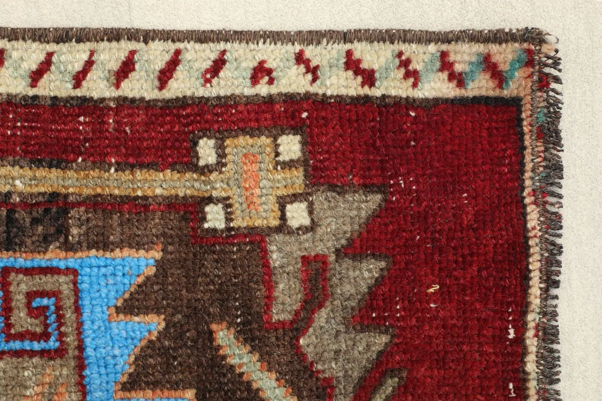 Side view of the border pattern, displaying the alternating beige and brown elements against the red field.