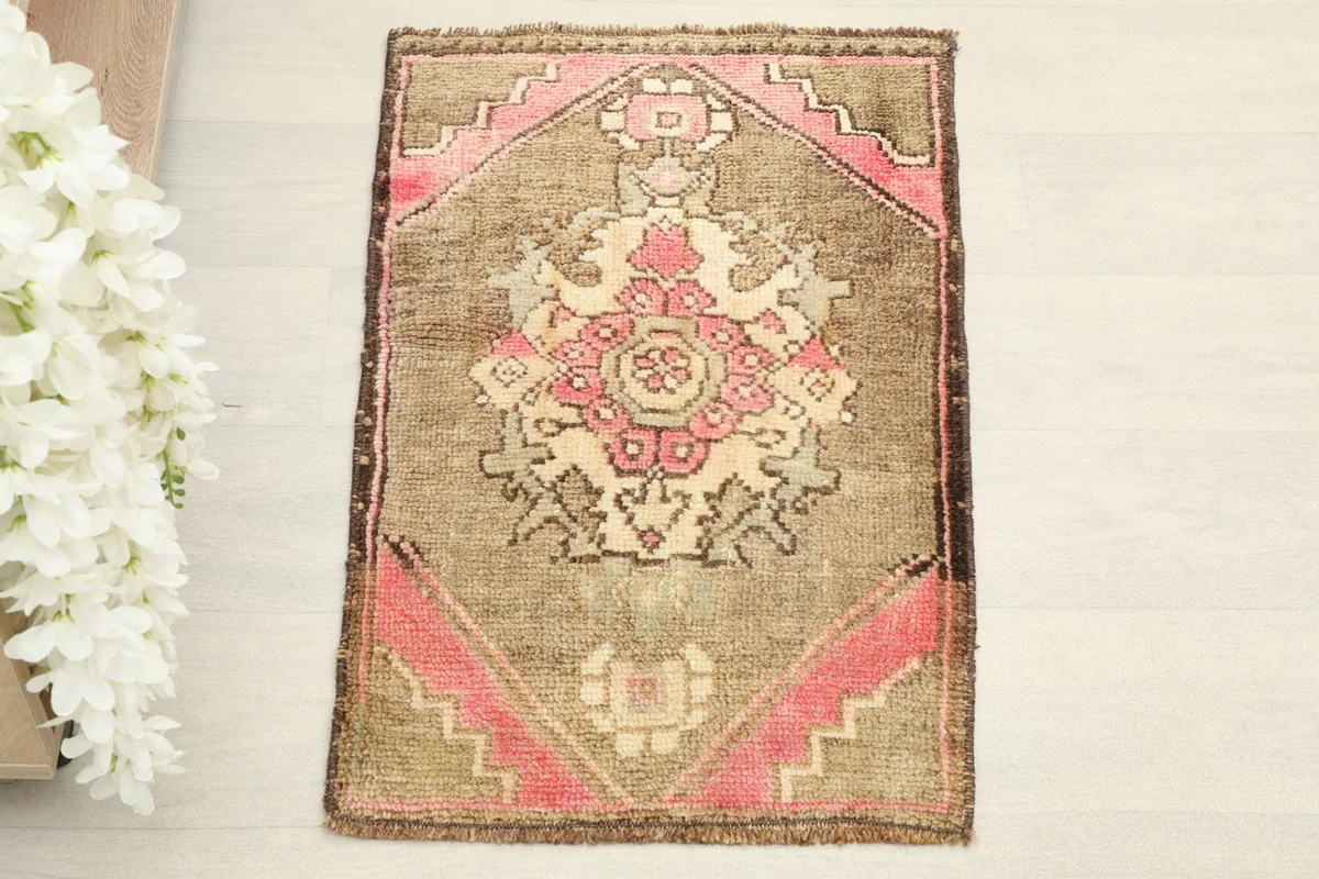 Overhead view of the small brown and pink vintage rug, showing the central medallion design