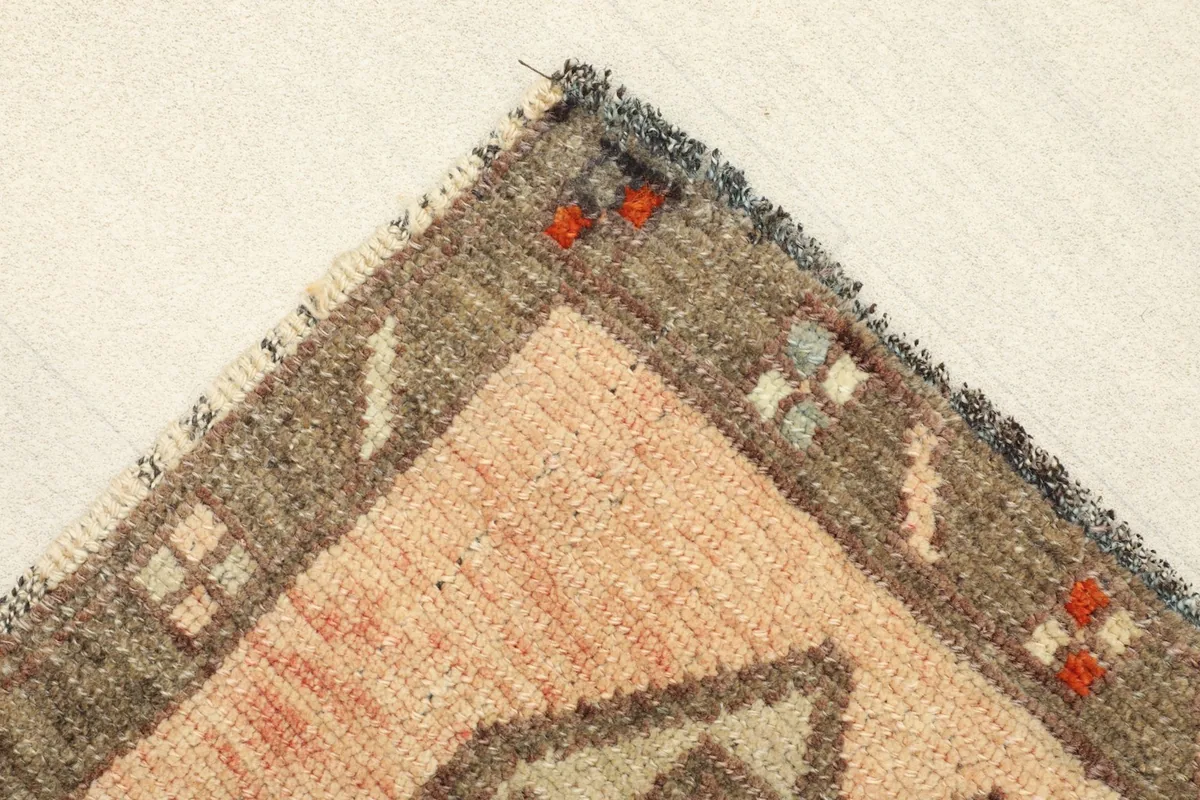 Corner detail of the rug, showing the charcoal border with small red and beige accents.