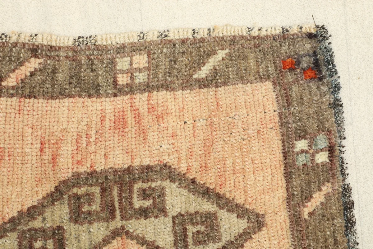 Close-up of the rug's border, highlighting the texture of the wool pile and the small decorative elements.