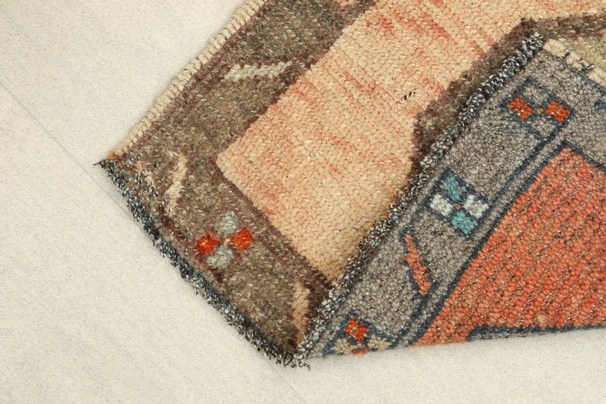 Angled view of the rug with a corner folded, revealing the reverse side and cotton foundation.