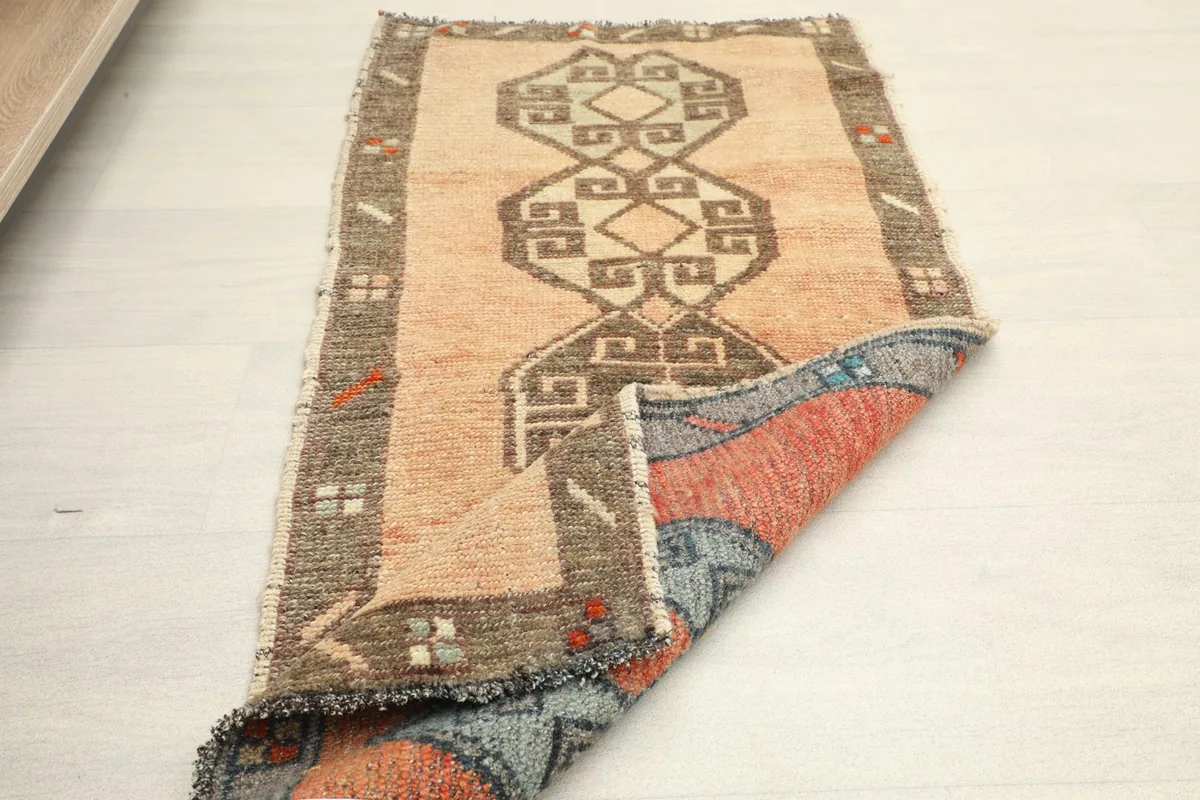Rug partially folded, showing the vibrant orange and blue colors on the reverse side of the foundation.