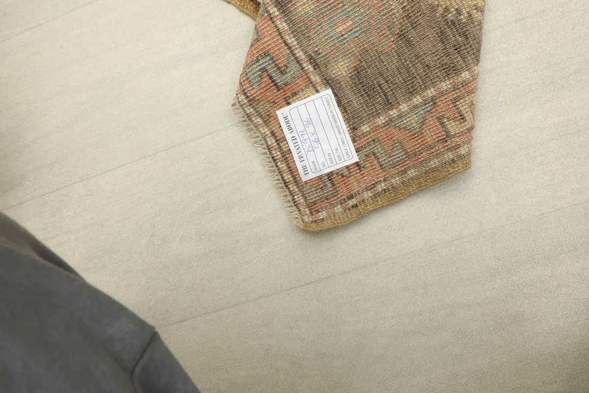 Underside of the hand-knotted rug, showing the cotton foundation and a product label