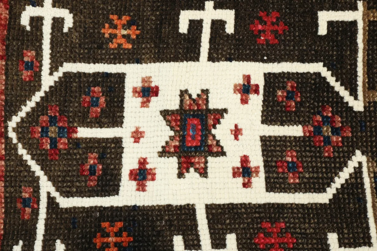 Close-up detail of the central ivory star motif with red and blue accents on the brown field.