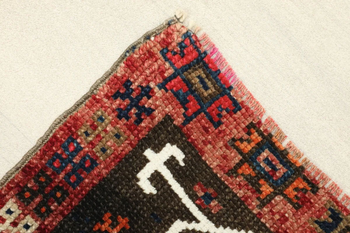 Corner detail of the doormat, showing the red border and the intricate hand-knotted pile.