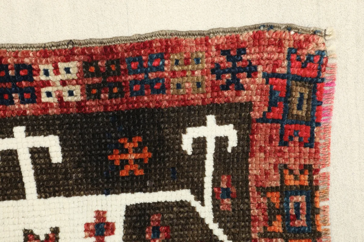 Close-up of the doormat's edge, revealing the vibrant red border and geometric elements.