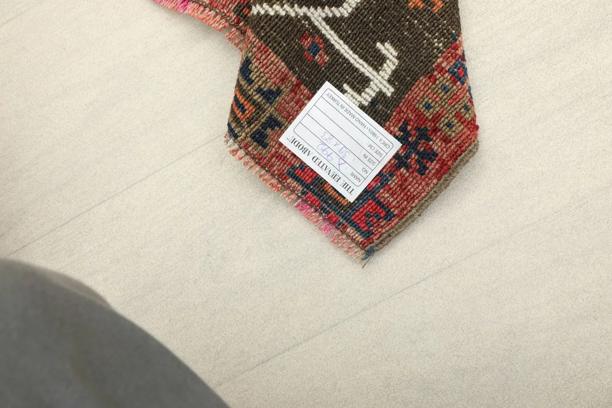 Underside of a corner of the rug, showing the hand-knotted cotton foundation and label.
