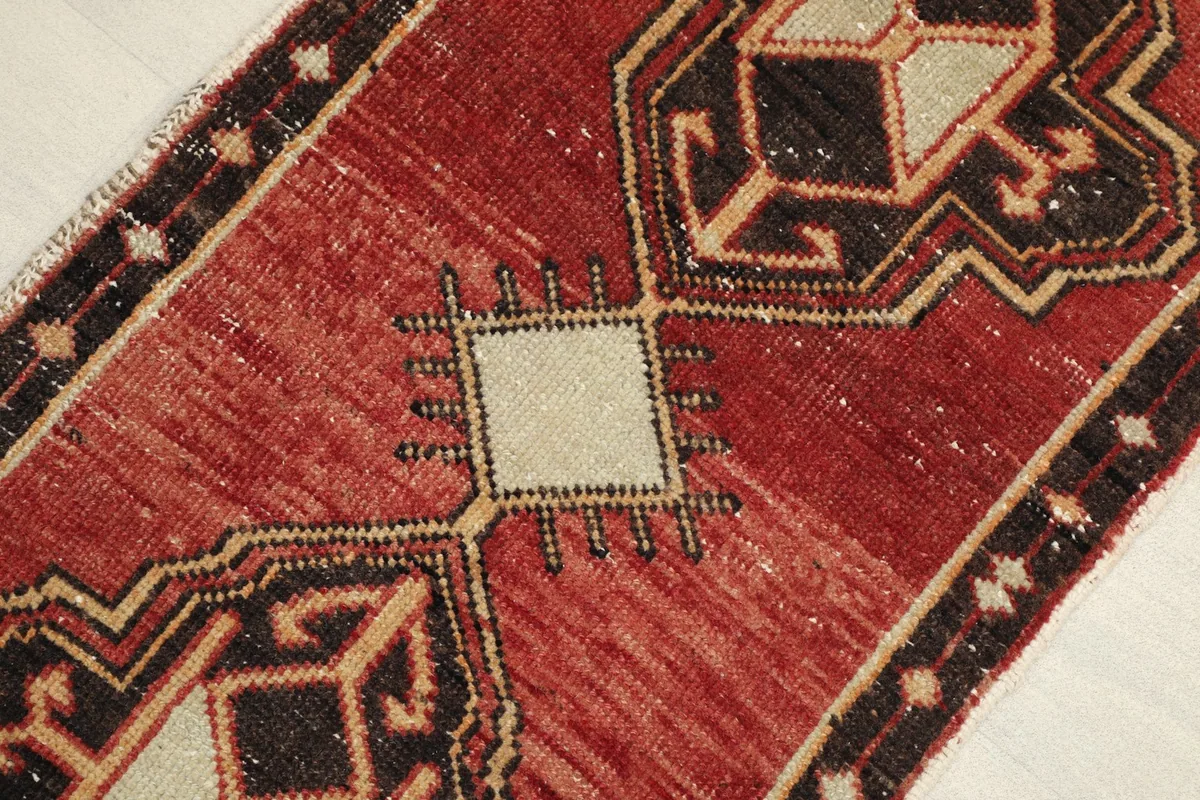 Close-up detail of the rug's red field, showing a central ivory square motif with black accents.