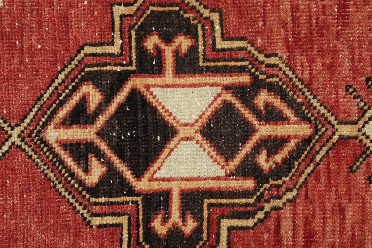 Detailed view of the rug's geometric pattern in black, red, and ivory colors.