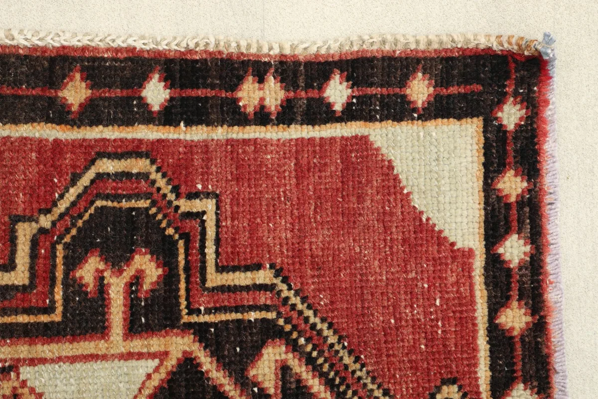 Close-up of the rug's edge, revealing the intricate border pattern and the red field.