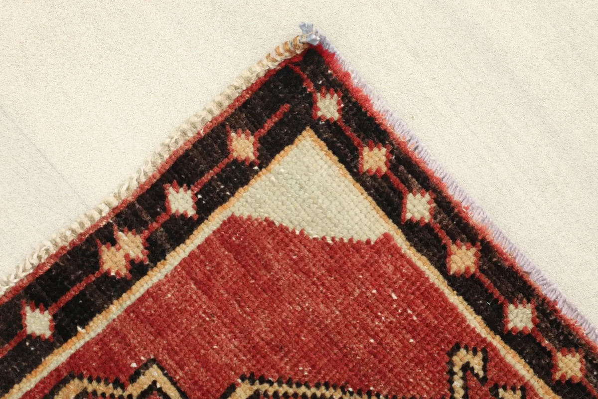 Corner detail of the rug, showing the black and ivory border design and fringe.
