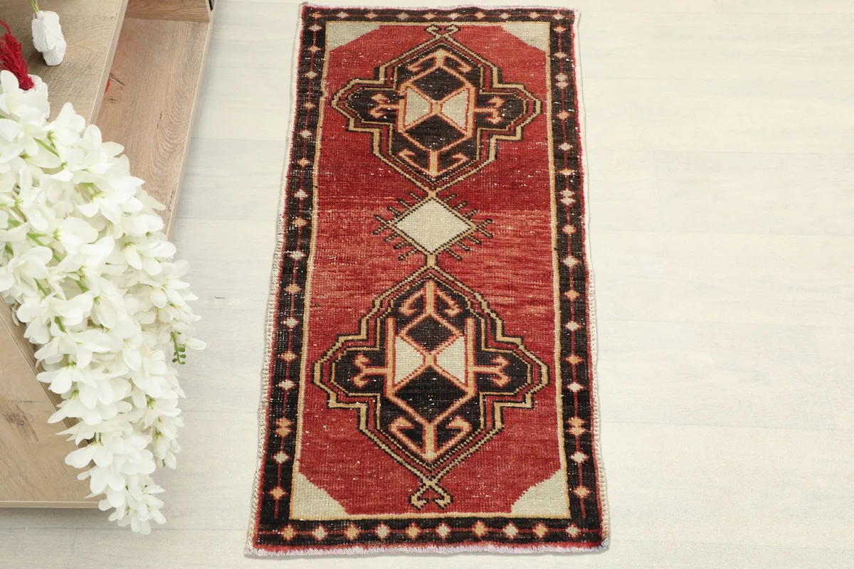 Overhead view of the vintage red rug, highlighting its central geometric motifs and border.