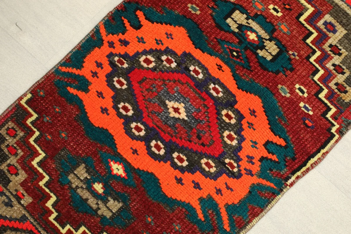 Angled view of the rug, highlighting the central orange medallion and geometric patterns.