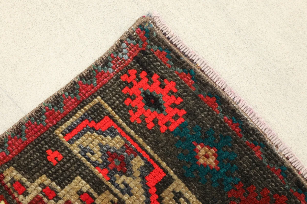Detail of the rug's corner, showing the charcoal border and fringe.