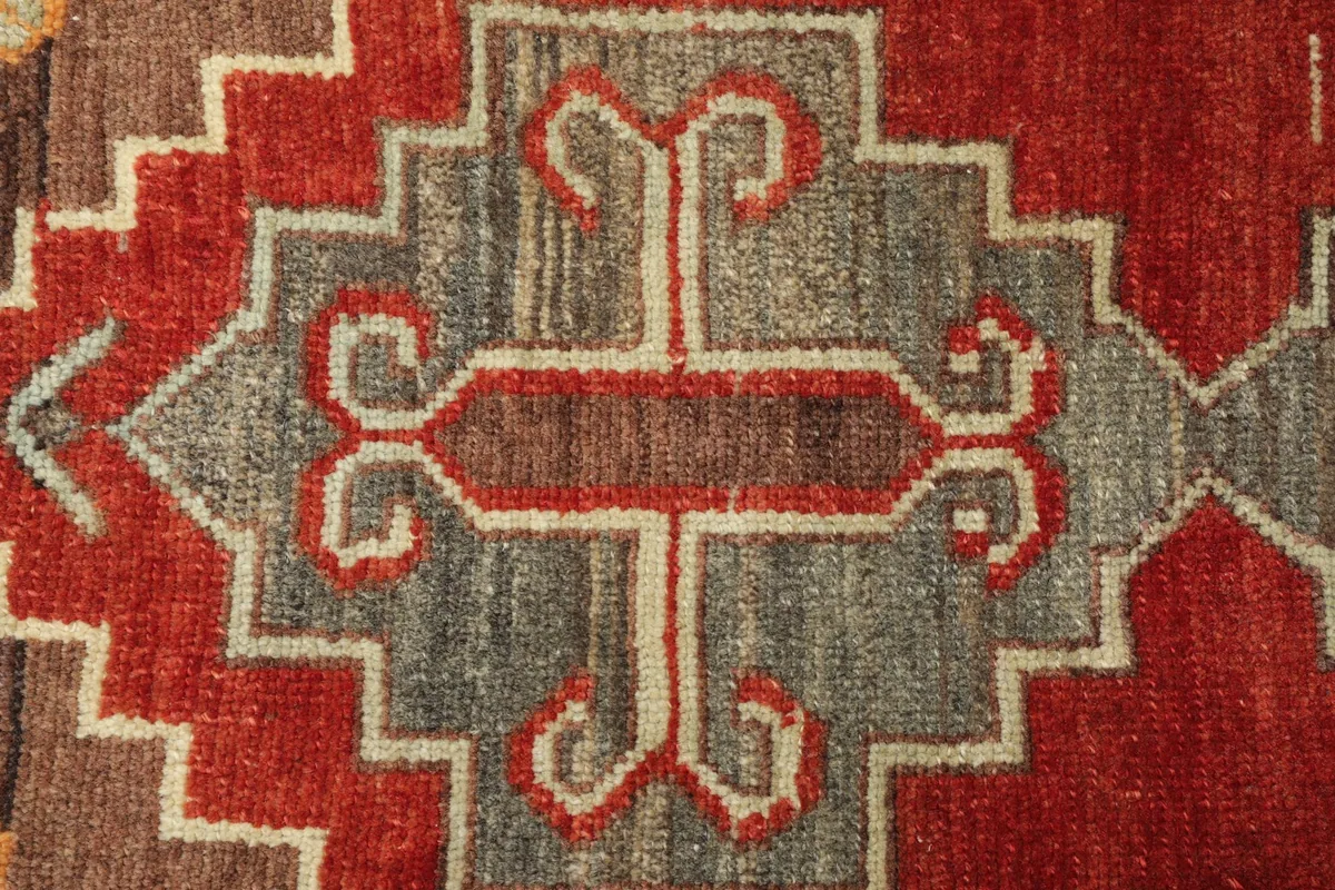Close-up detail of the central geometric motif in rust and gray tones
