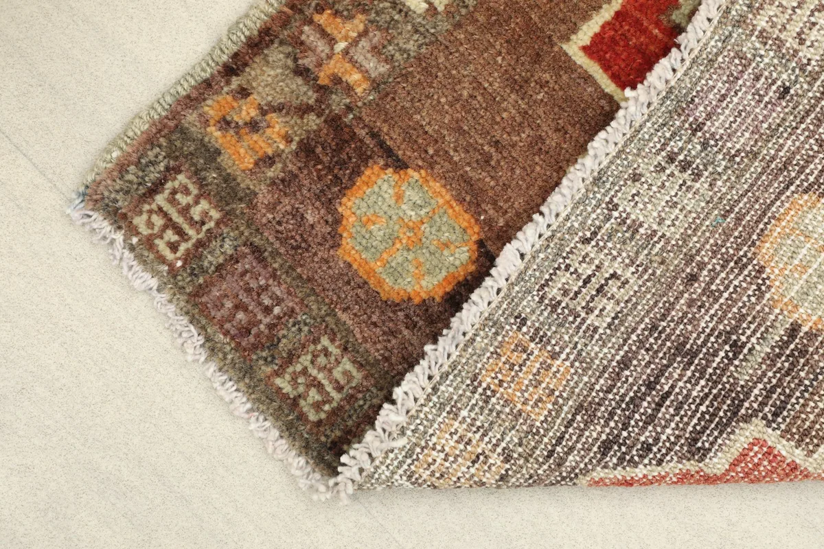 View of the rug folded to show the wool pile on cotton foundation and intricate patterns