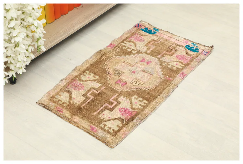 Full top view of the 1'7" x 2'10" brown and pink geometric Anatolian rug on a light floor.