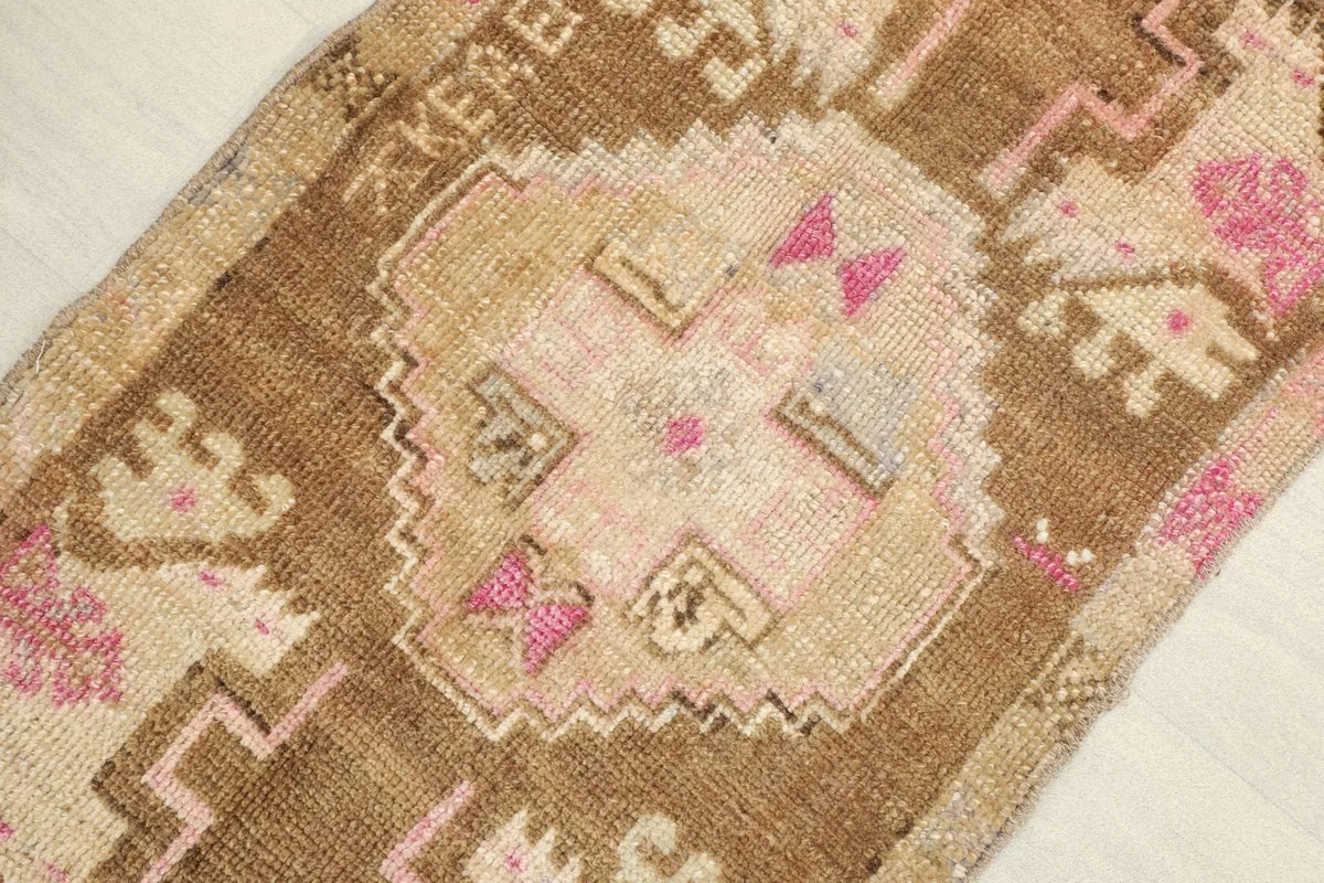 Close-up detail of the central geometric motif in brown, pink, and beige tones.
