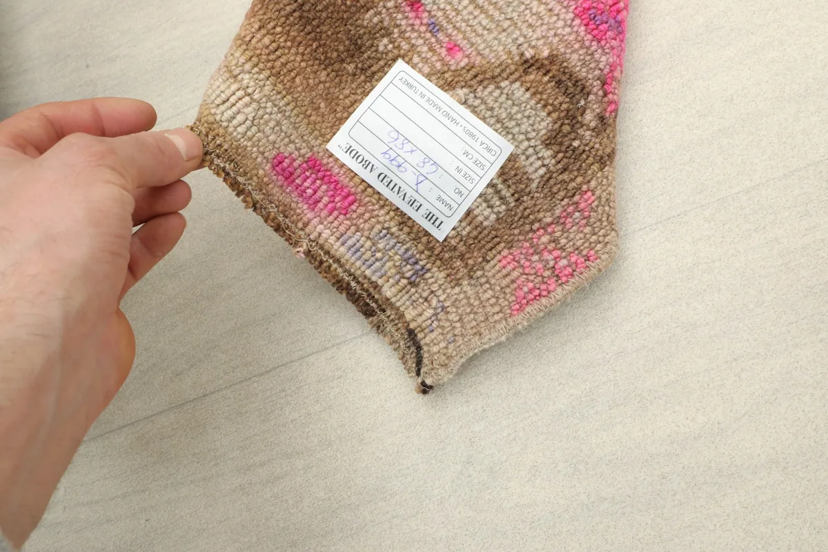 Hand holding a folded corner of the rug, showing the reverse side and a product tag.