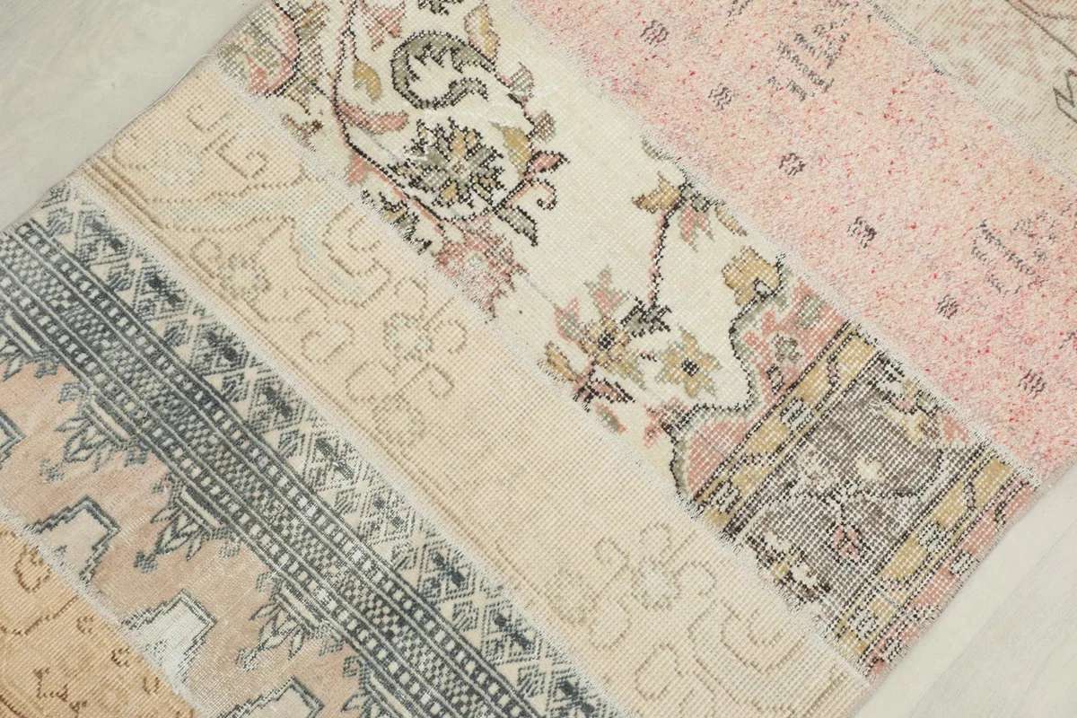 Detailed view of various patchwork sections, including floral and tribal motifs with hints of gray and ivory
