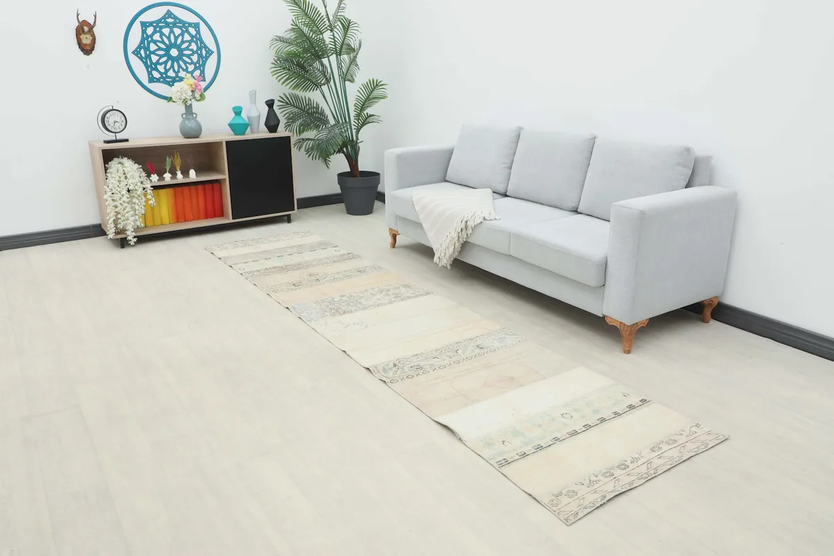 Vintage runner rug laid out in a modern living room setting next to a light gray sofa.