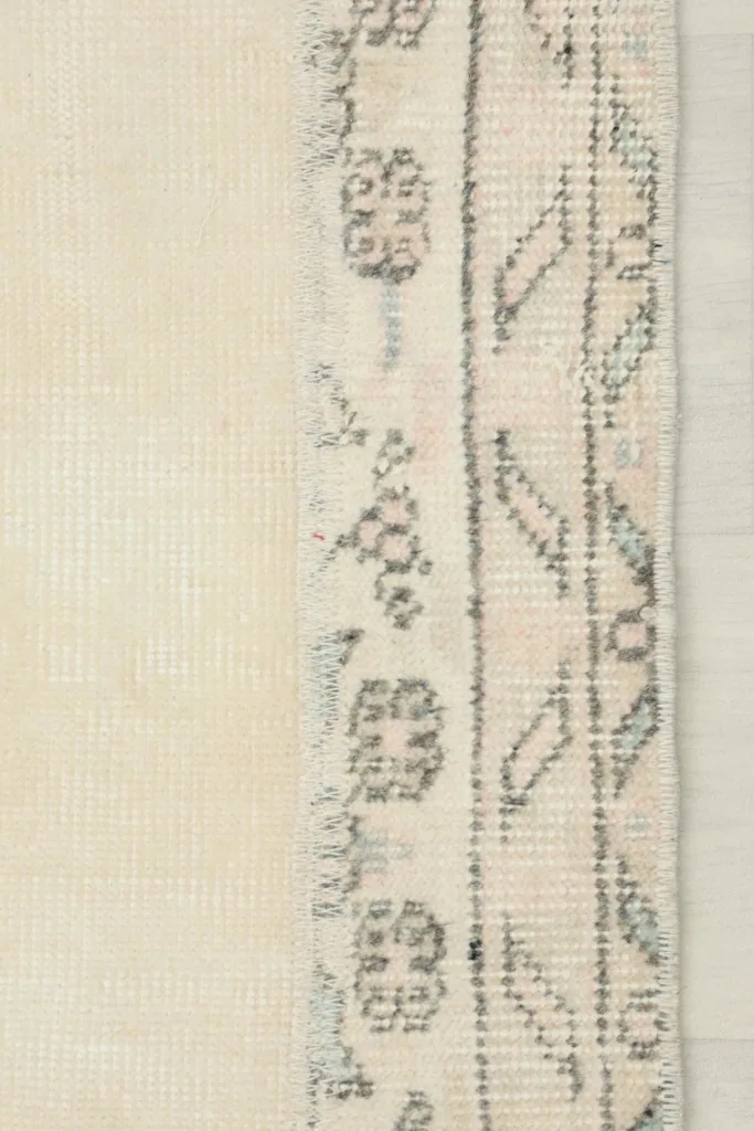 Edge of the runner showing the subtle patterned border and the tight weave of the wool pile.