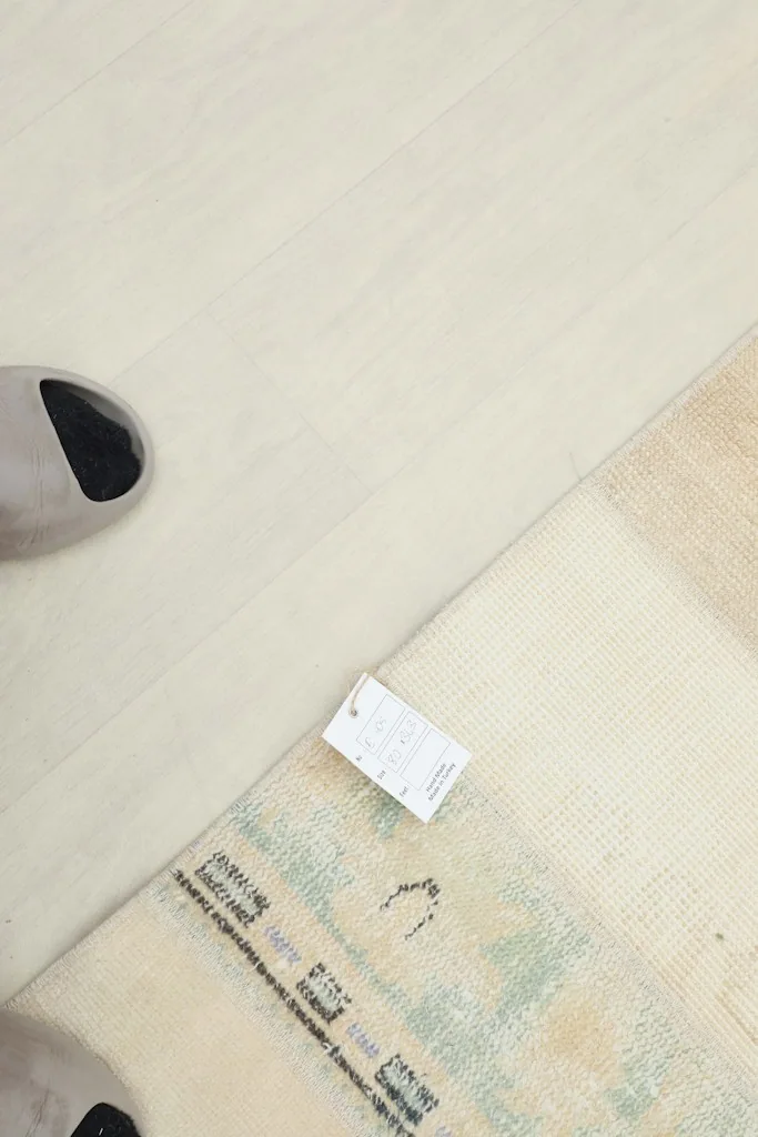 Overhead view showing the rug's texture and a small tag, with a foot for scale.