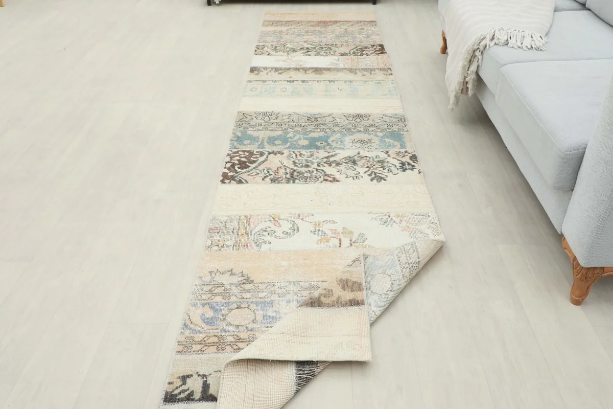 Runner rug partially folded at the end, showing its length in a room alongside a light-colored sofa