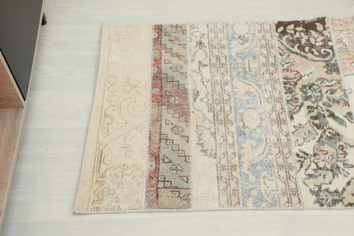Detailed view of rug sections featuring rust, beige, and blue patterns within the patchwork