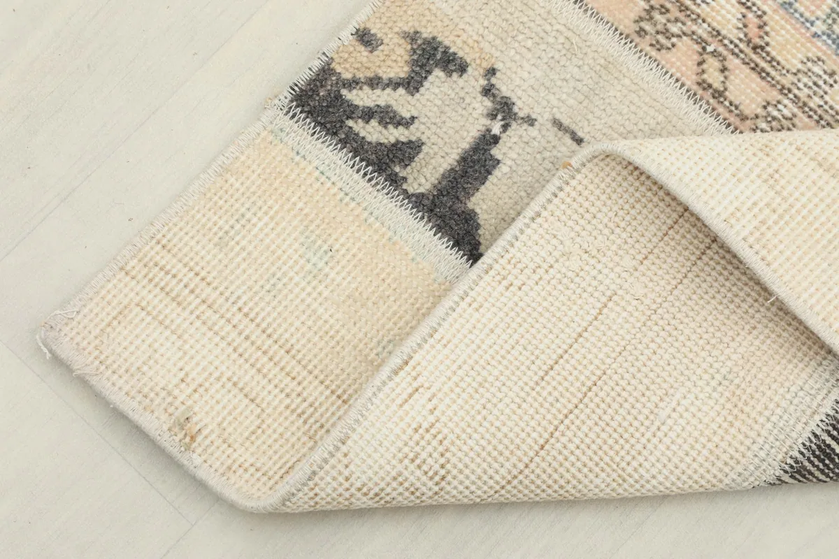 Corner of the runner rug folded back to display the underside and the texture of the wool pile