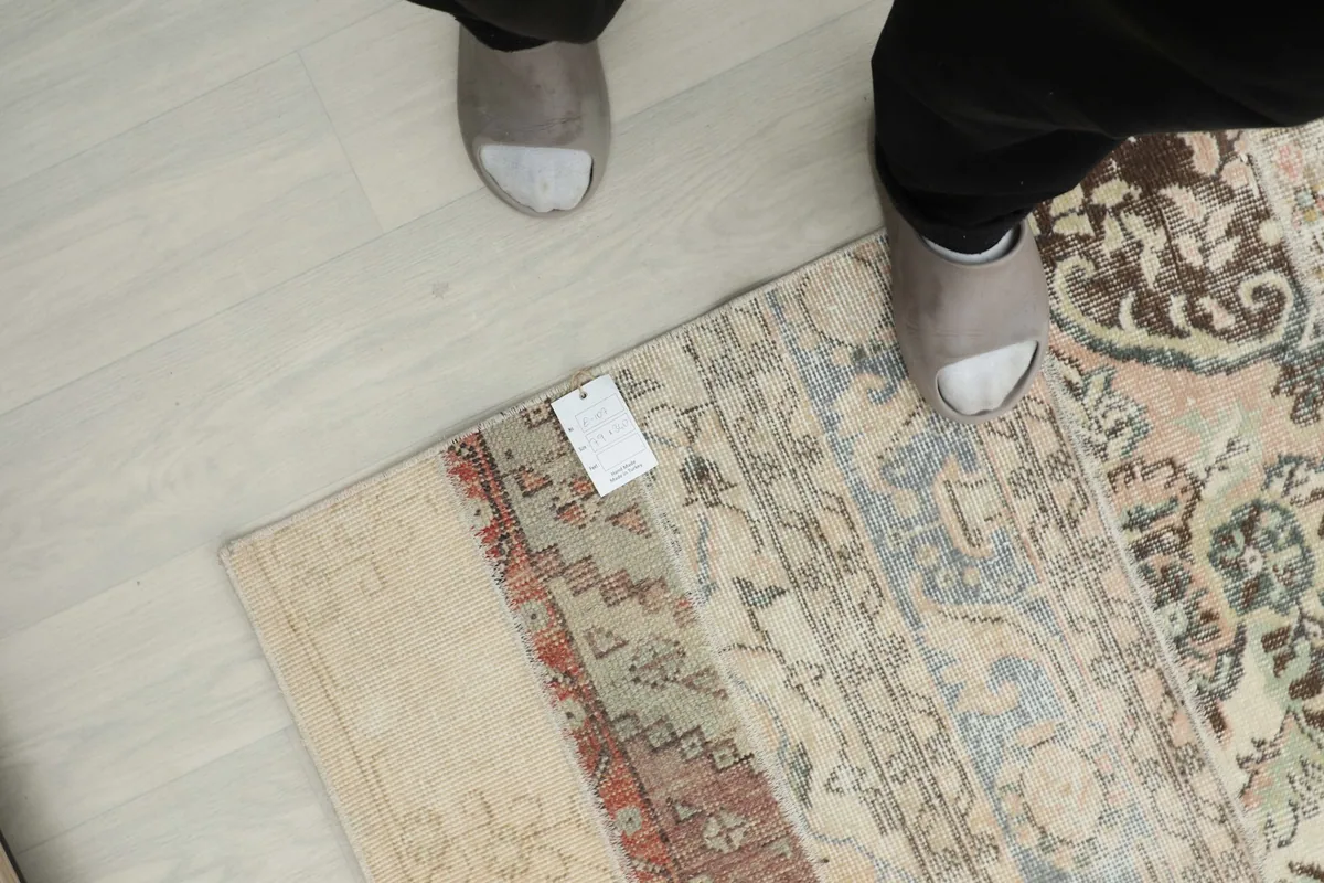 Overhead perspective of the rug with feet for scale, showcasing the varied patchwork sections