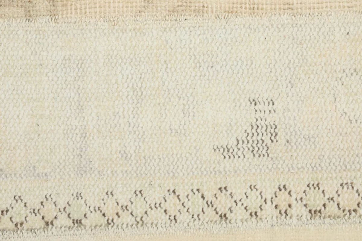 Close-up of a cream section with a subtle, faded border pattern and textured weave