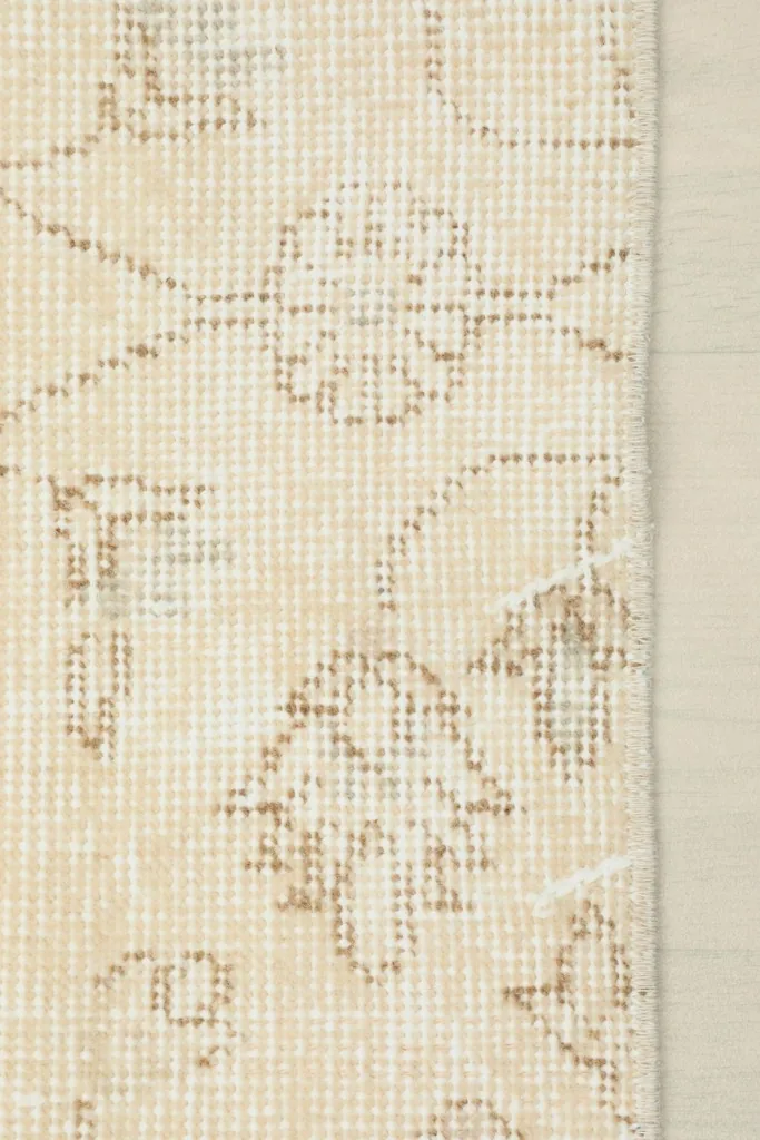 Detailed shot of the low wool pile and hand-knotted texture with faded beige patterns
