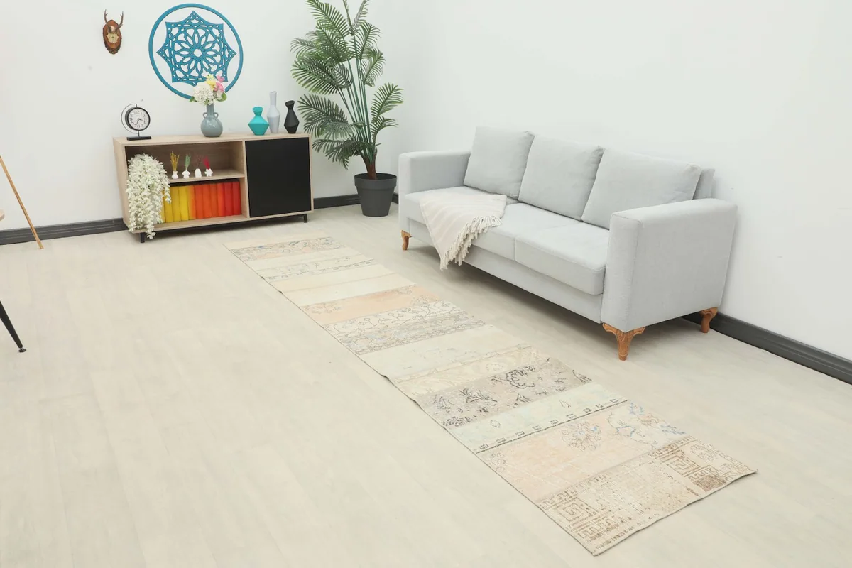 Long beige patchwork runner rug extending from a sofa in a modern living space