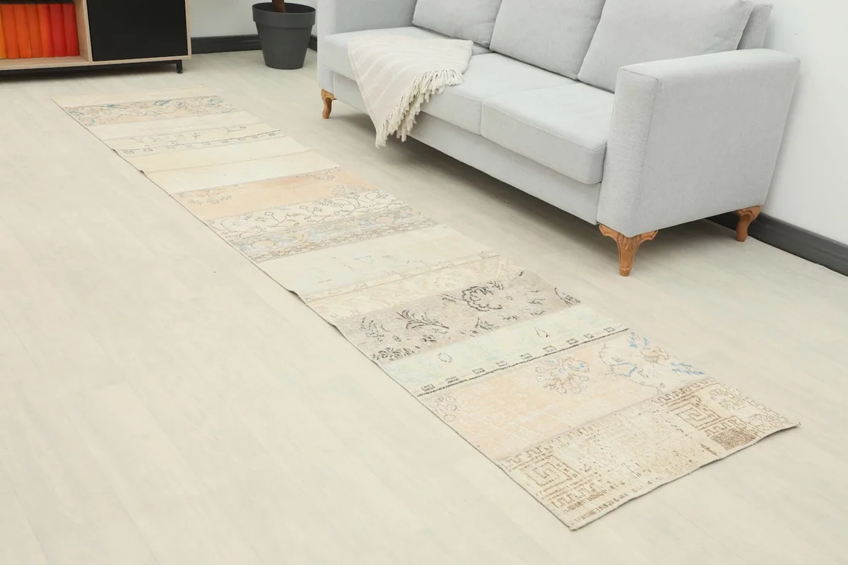 Close-up angled view of the beige patchwork runner rug in a room setting