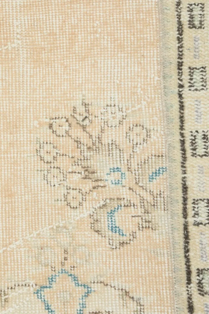 Macro detail of a beige patch with a faint floral motif in blue and brown