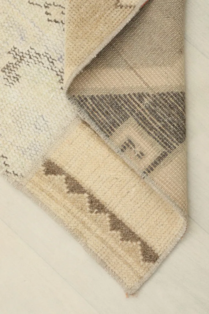Corner of the runner rug folded to show the thickness and back of the hand-knotted wool.