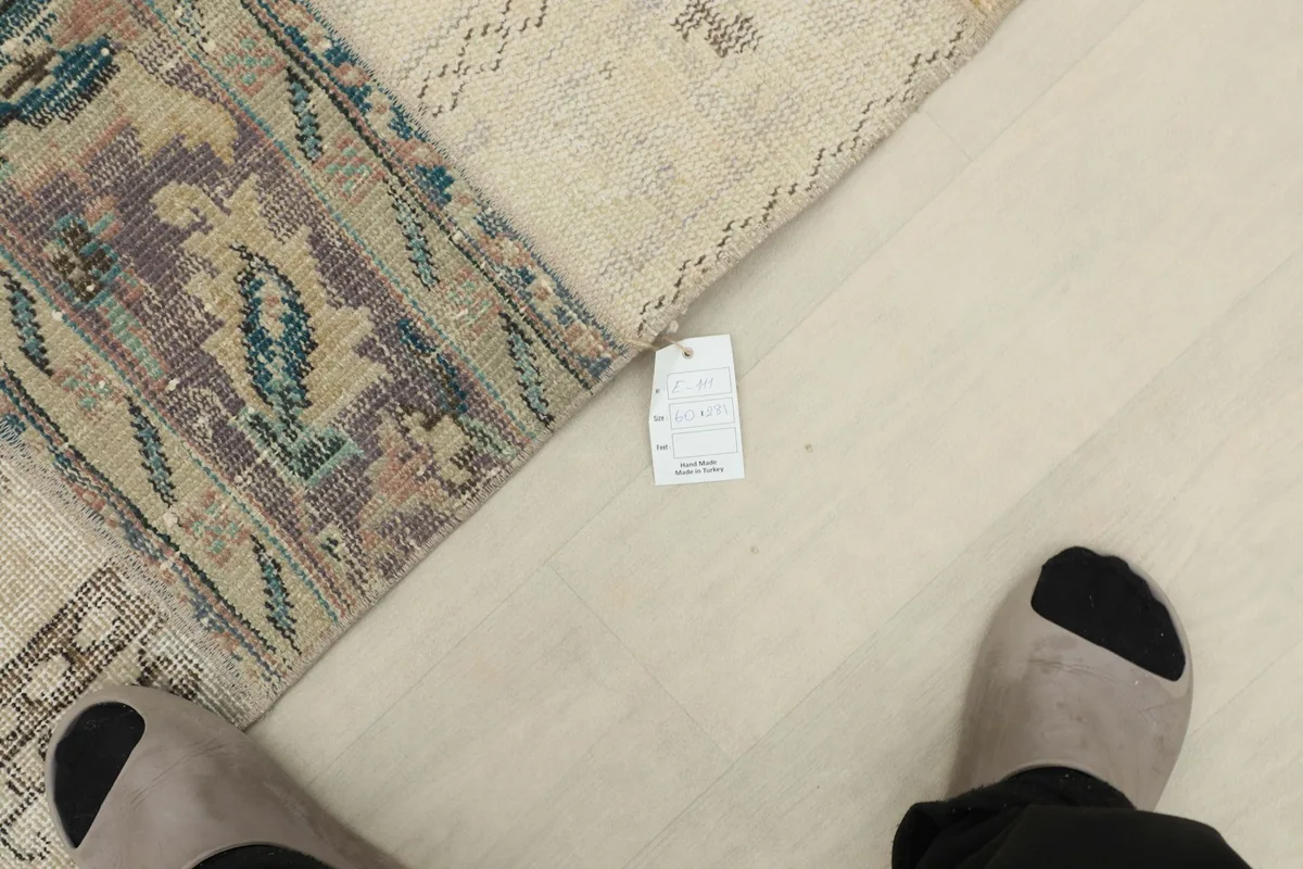 View of the runner rug with a size tag visible near the edge, showing scale relative to feet.