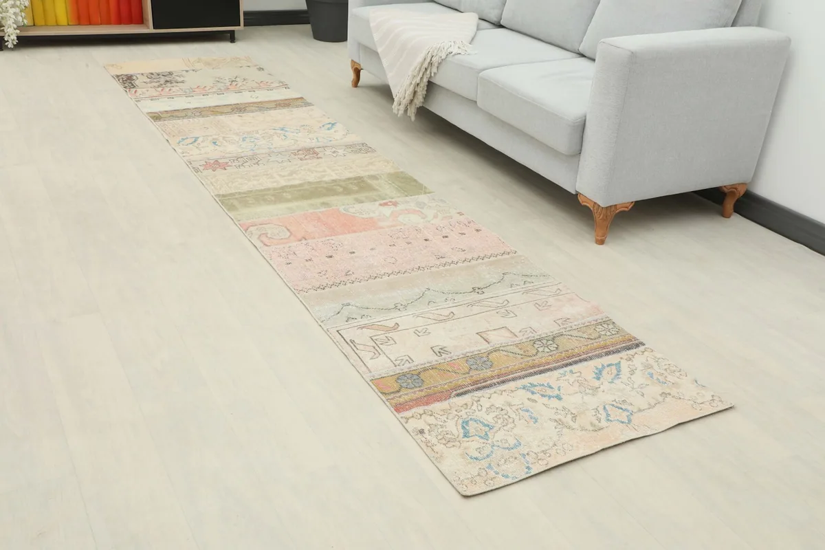 Angled view of the multicolor patchwork runner rug in a hallway beside a light gray sofa