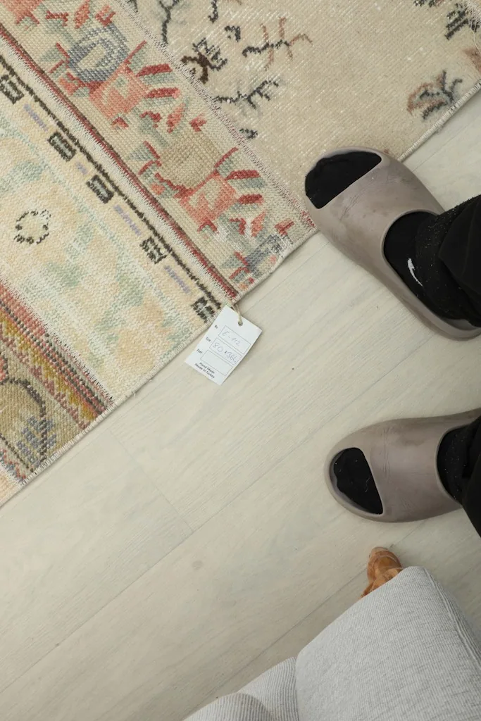 Overhead view of the rug's surface next to a person's feet, showing scale and texture