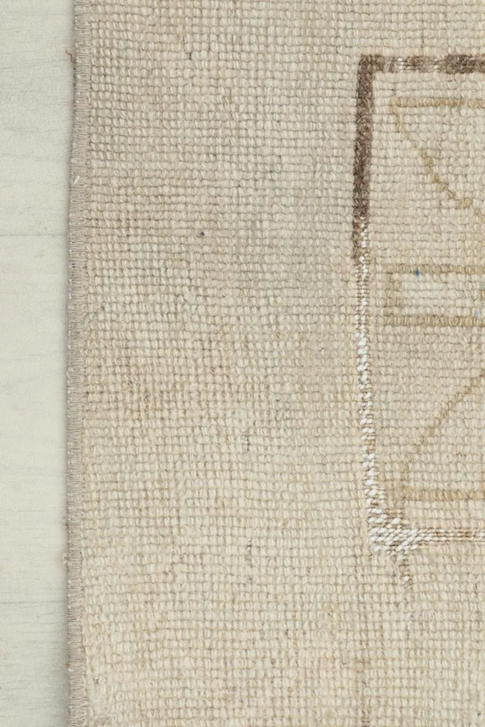 Side view of the rug's edge, showcasing the low wool pile and hand-knotted texture