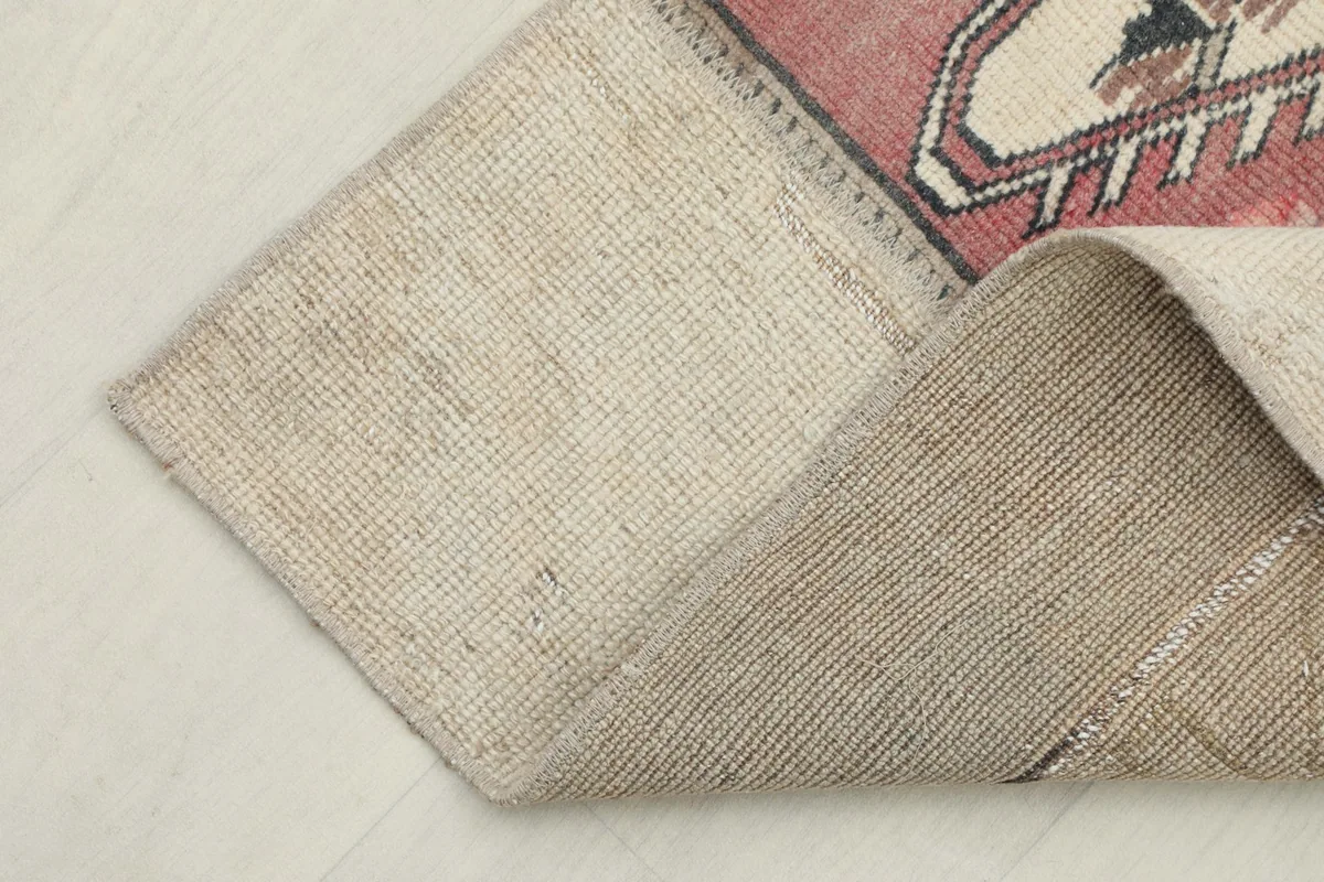 Corner of the rug folded to reveal the cotton foundation and hand-knotted construction