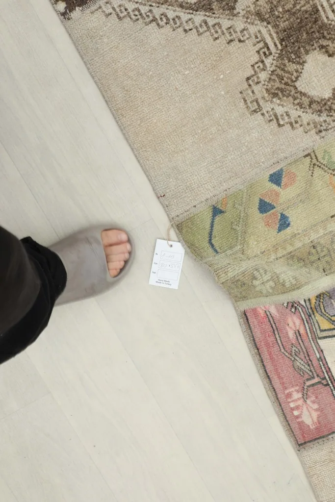 Overhead detail shot of the rug's surface next to a foot, showing scale and texture