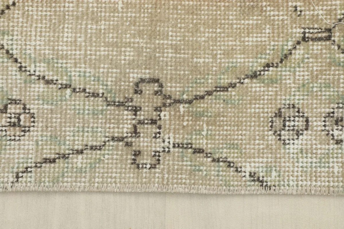 Close-up of a distressed patch with a geometric pattern in gray and olive tones